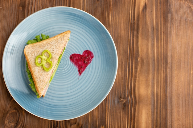 delizioso panino con insalata di pomodori verdi e prosciutto all'interno della piastra sul marrone