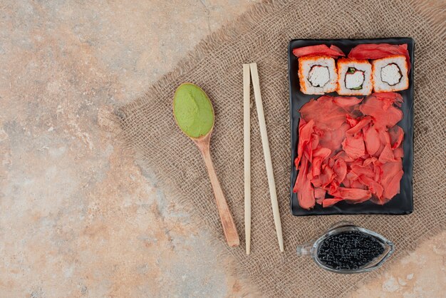 Delizioso sushi con caviale, zenzero e vasabi sul piatto di legno