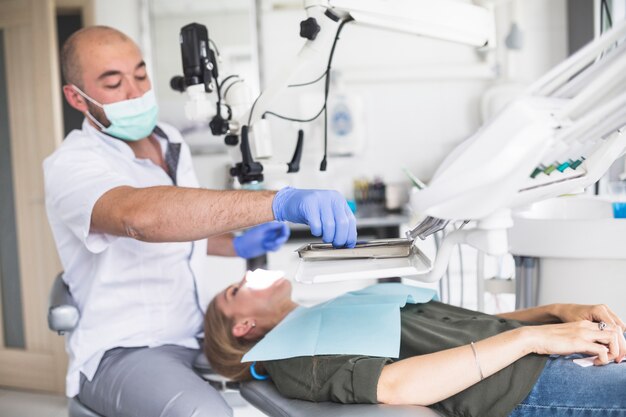 Dentista che controlla i denti di una donna che si trova sulla sedia dentale