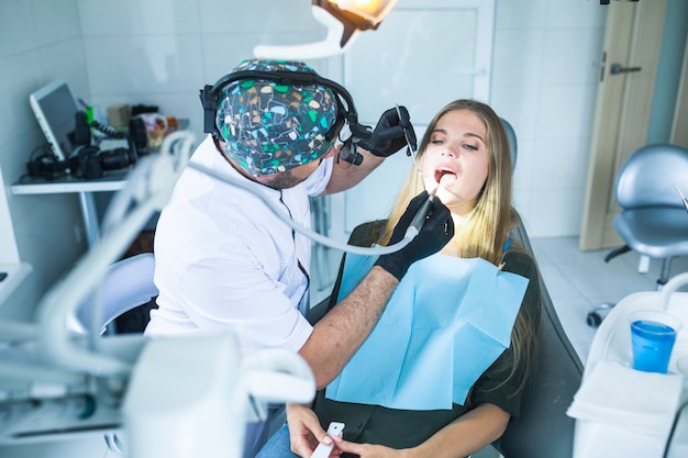 Dentista che cura i denti del paziente femminile