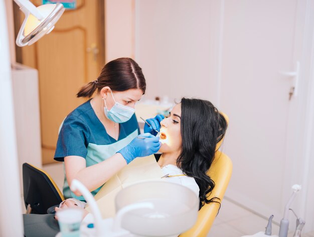 Dentista che esamina i denti dei pazienti in clinica