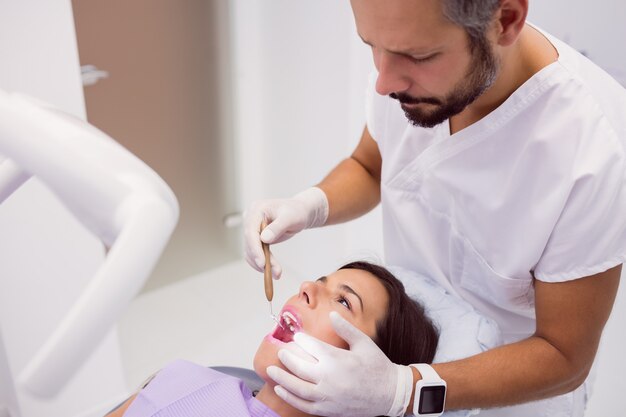 Dentista che esamina i denti pazienti femminili con uno specchio di bocca