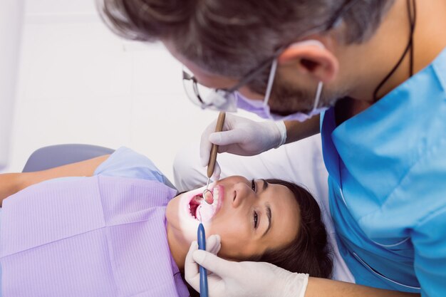 Dentista che esamina un paziente femminile con gli strumenti