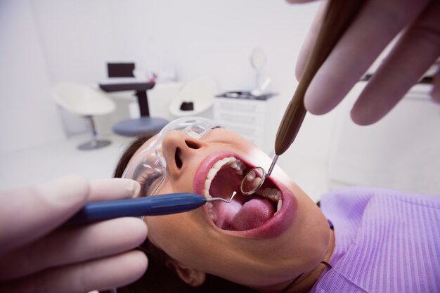 Dentista che esamina un paziente femminile con gli strumenti