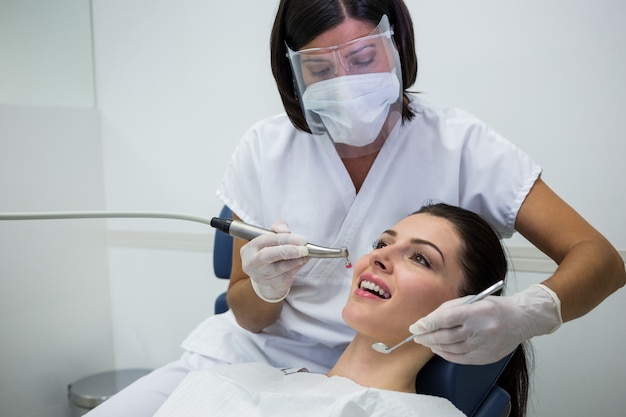 Dentista che esamina un paziente femminile con gli strumenti