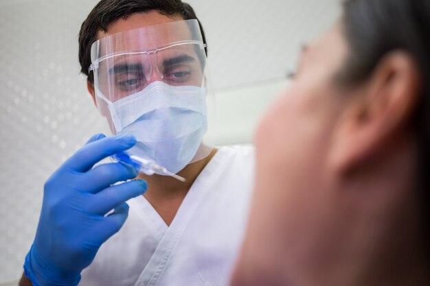 Dentista che fa l'iniezione al paziente femminile