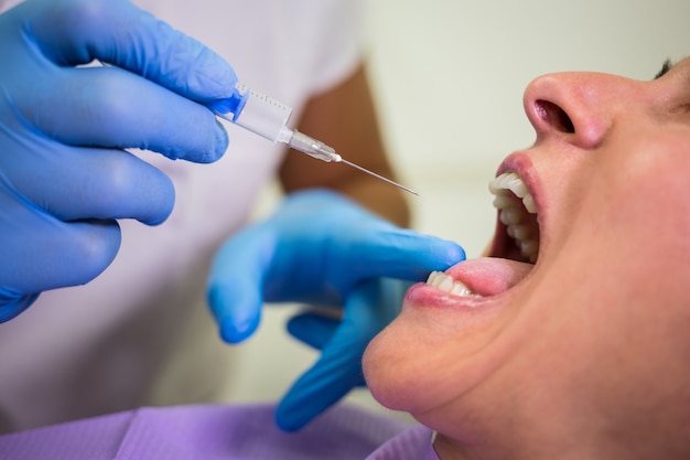 Dentista che fa l'iniezione al paziente femminile