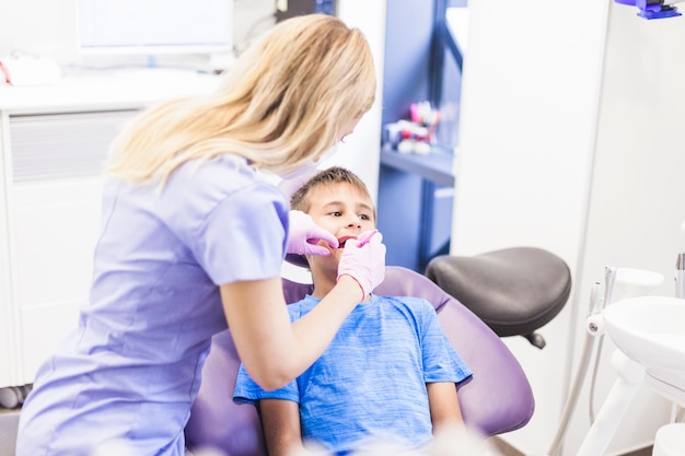 Dentista che fa trattamento dentario di un ragazzo in clinica