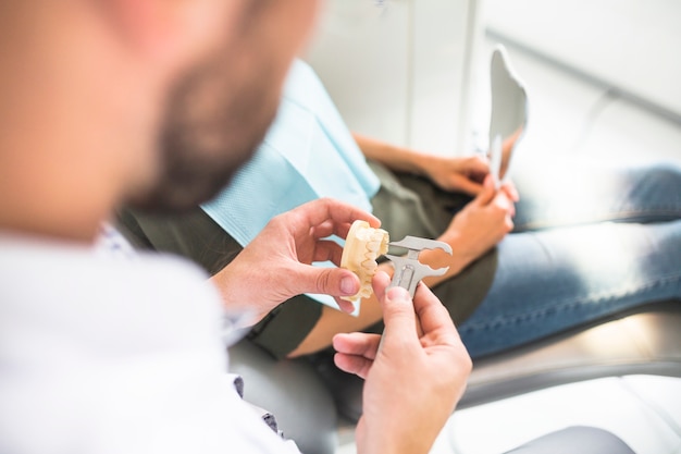 Dentista che misura il modello dei denti di plastica con il calibro a corsoio