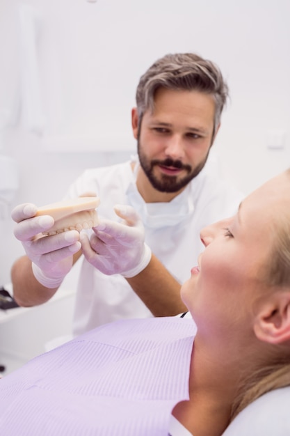 Dentista che mostra il modello della protesi dentaria al paziente