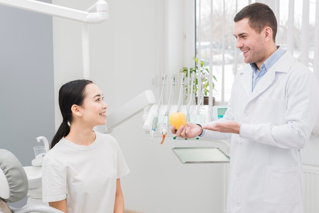 Dentista che mostra mela al paziente