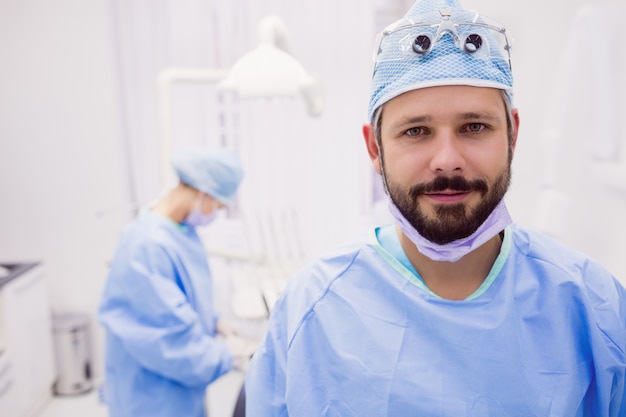 Dentista che sorride e che posa alla clinica dentale