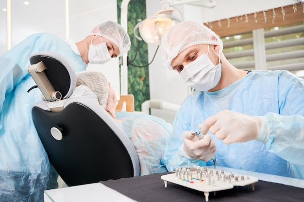 Dentista e il suo assistente che lavorano con un paziente su una poltrona del dentista nell'ufficio del dentista