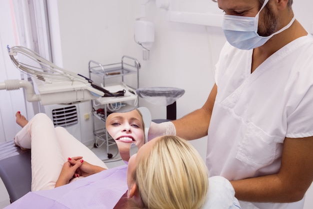 Dentista in possesso di uno specchio di fronte al paziente