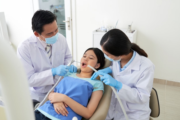 Dentista maschio asiatico e infermiere femminile che trattano cavità in clinica