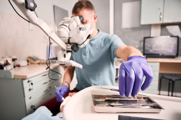 Dentista maschio che afferra l'esploratore dentale durante la procedura dentale