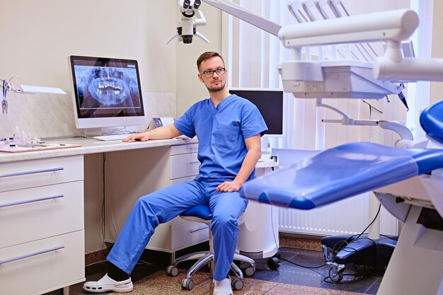 Dentista maschio che esamina i raggi x dei denti sul computer in uno studio dentistico.