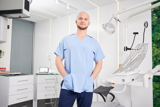 Dentista maschio di bell'aspetto in piedi in studio dentistico