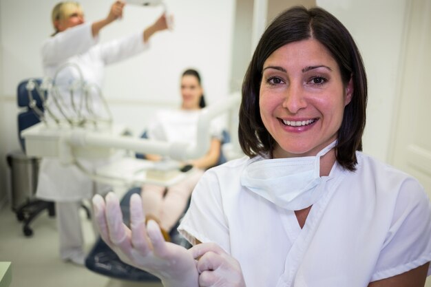 Dentista sorridente che indossa i guanti chirurgici