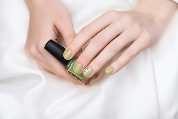 Design delle unghie verde. Mano femminile con manicure glitterata.