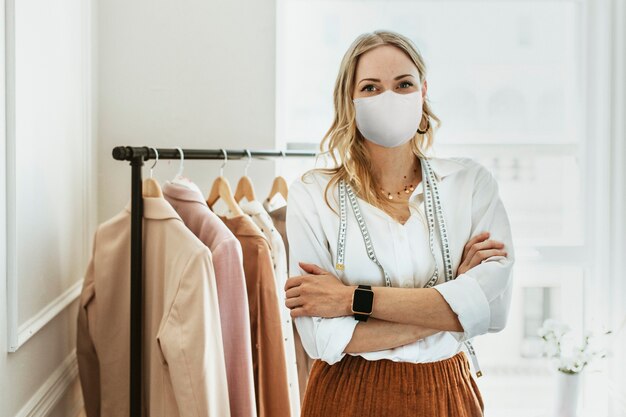 Designer in una nuova normale boutique che indossa una maschera, covid 19