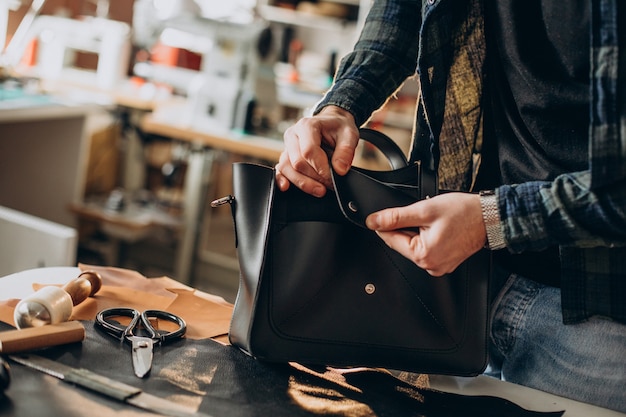 Designer maschio e sarto in pelle che lavora in una fabbrica da vicino