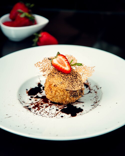 Dessert con sciroppo di cioccolato e fetta di fragola in cima