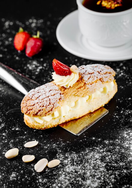 Dessert francese di eclair con panna da montare e fragole.