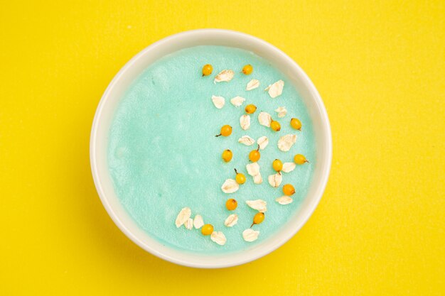 Dessert ghiacciato blu di vista superiore all'interno del piatto sul colore del cereale del latte della tabella gialla