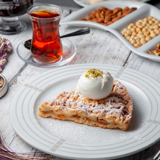 Dessert in un piatto con tè, vista matta dell'angolo alto su un fondo di legno bianco