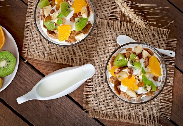 Dessert sano con muesli e frutta in una ciotola di vetro sul tavolo