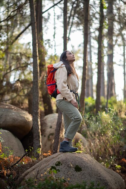 Determinata viandante nella foresta. Donna con zaino con abiti casual in piedi sulla collina. Natura, tempo libero, concetto di hobby