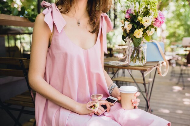 Dettagli di mani di donna seduta nel caffè in abito di moda estiva, abito di cotone rosa, occhiali da sole, bere caffè, accessori eleganti, relax, abbigliamento alla moda