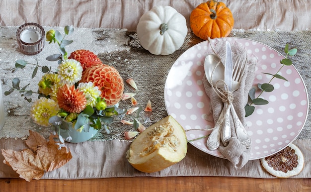 Dettaglio del primo piano dell'arredamento di una tavola festiva autunnale con zucche, fiori.