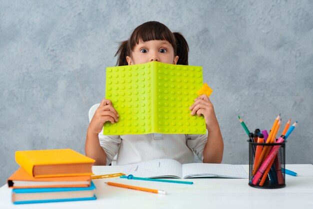 Di nuovo a scuola. Scolara sveglia del bambino che si siede ad uno scrittorio in una stanza.