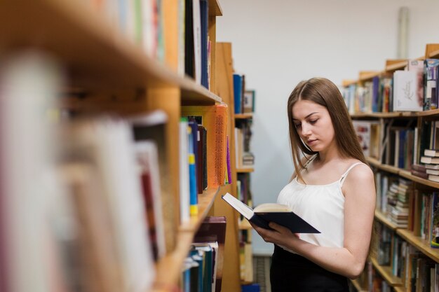 Di nuovo al concetto della scuola con la donna che studia nella biblioteca