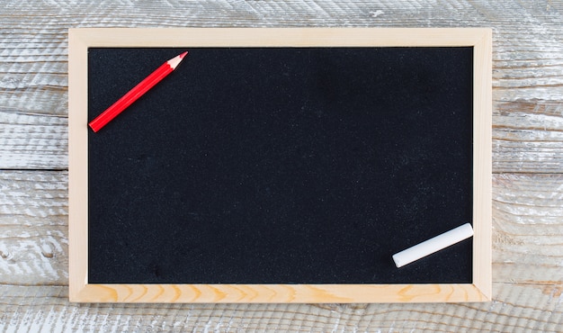 Di nuovo al concetto della scuola con la matita, gesso sulla disposizione piana del fondo di legno.