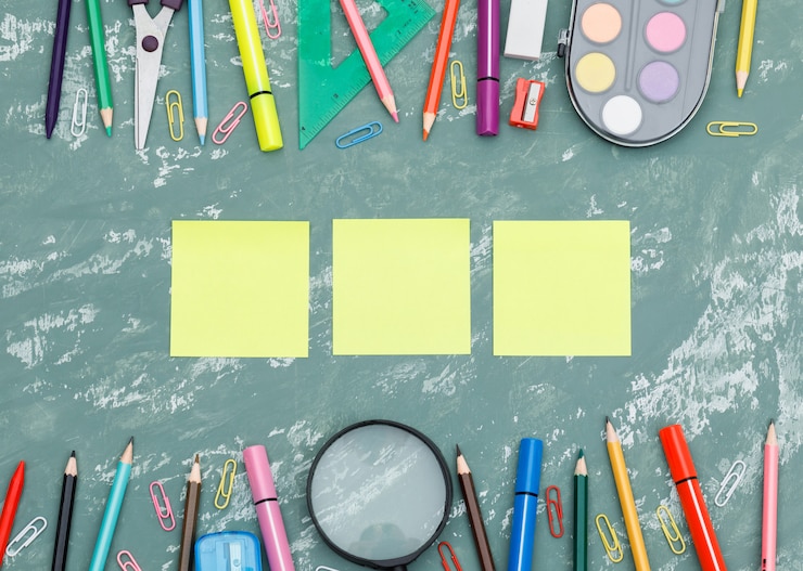 Foto gratuito di nuovo al concetto della scuola con le note appiccicose, la lente d'ingrandimento, i rifornimenti di scuola sulla disposizione piana del fondo del gesso.