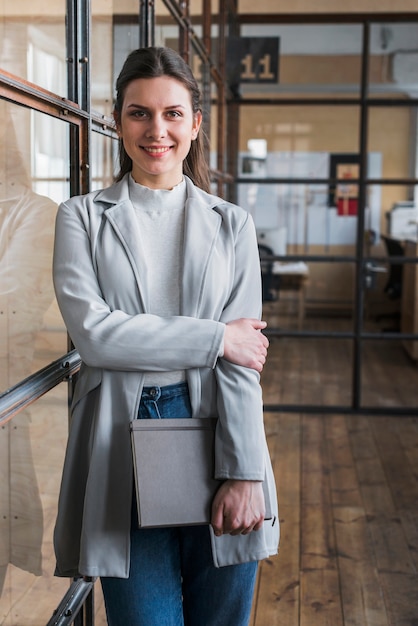 Diario felice della holding della giovane donna di affari che esamina macchina fotografica nel luogo di lavoro