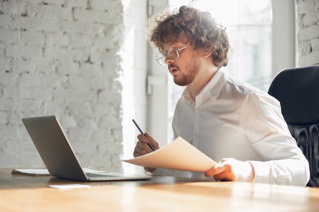 Digitazione di testo, analisi, navigazione. Giovane caucasico in abiti da lavoro che lavora in ufficio. Giovane donna d'affari, manager che svolge attività con smartphone, laptop, tablet ha una conferenza online, studia.