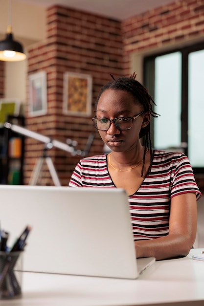 Dipendente che lavora a distanza, digita sulla tastiera del laptop, scrive e-mail, seduto alla scrivania in ufficio a casa. Libero professionista professionista in copywriting per occhiali, apprendimento degli studenti tramite computer