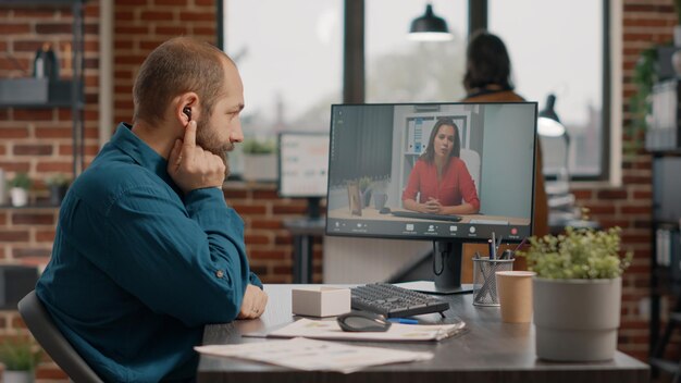 Dipendente che parla con il manager tramite videochiamata e auricolari sul computer alla scrivania. Uomo d'affari che partecipa alla riunione con il collega per discutere la strategia di marketing in una videoconferenza online remota.