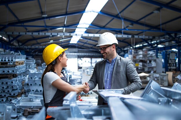 Direttore di fabbrica che visita la linea di produzione e si congratula con il lavoratore per la promozione per il duro lavoro e i buoni risultati