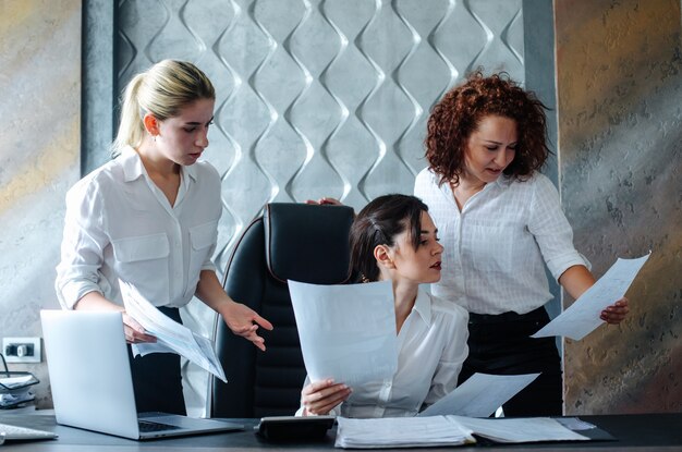 Direttore femminile della giovane signora di affari che si siede alla scrivania che utilizza la riunione d'affari del processo di lavoro del computer portatile che lavora con i colleghi che risolvono il concetto collettivo dell'ufficio di attività di affari