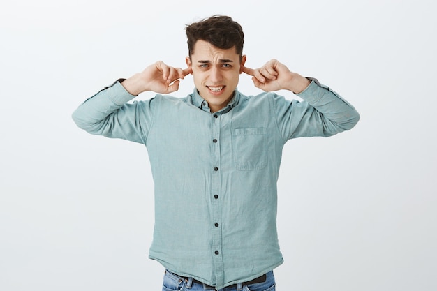 Disattiva la canzone fastidiosa. Ragazzo europeo scomodo scontento in camicia casual