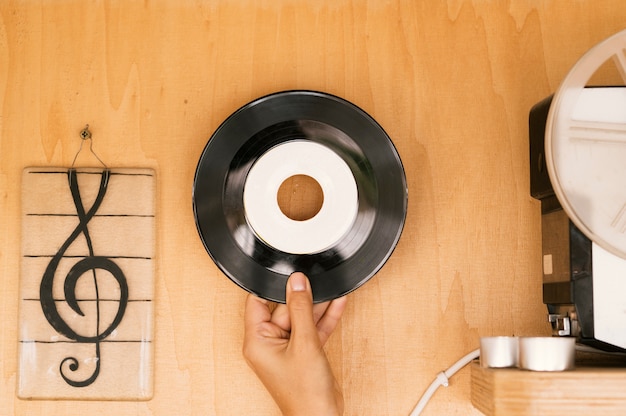 Disco del vinile della tenuta della persona sulla tavola di legno