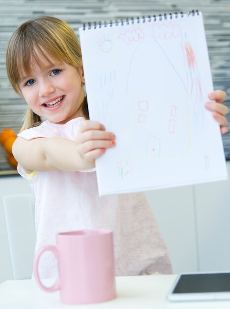 Disegno a bambino con pastelli, seduto a tavola in cucina a casa