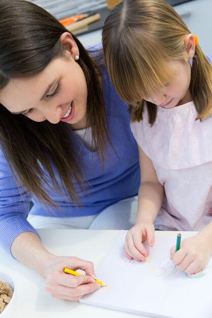 Disegno del bambino con i pastelli con la sua mamma a casa