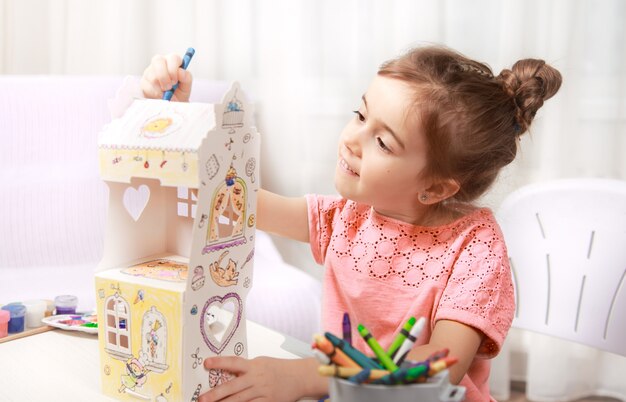 Disegno sveglio della bambina con le matite a casa