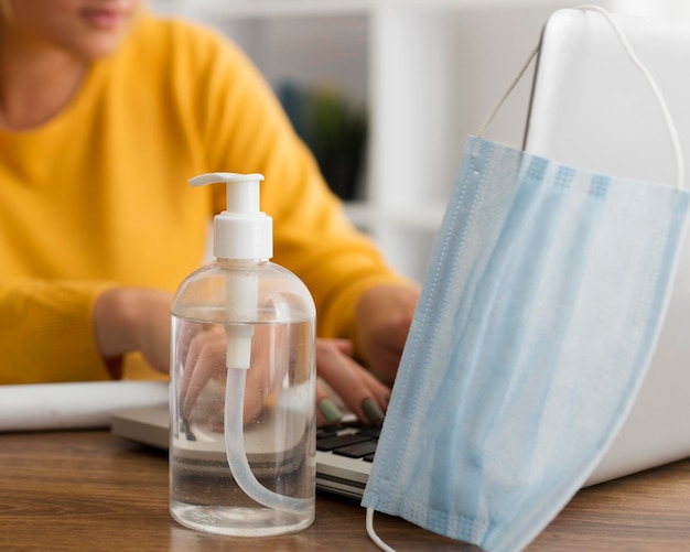 Disinfettante di primo piano con maschera facciale sulla scrivania